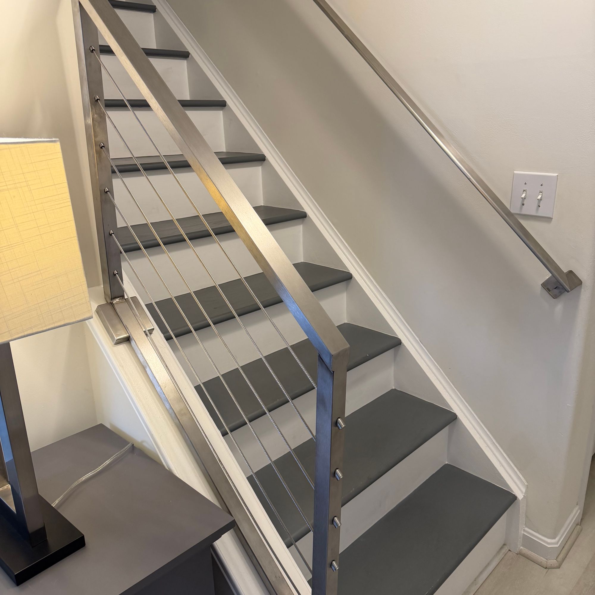 Modern staircase with dark treads, white risers, and cable railing system in residential interior