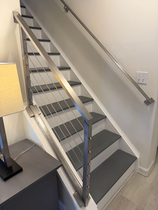 Modern staircase with dark treads, white risers, and cable railing system in residential interior