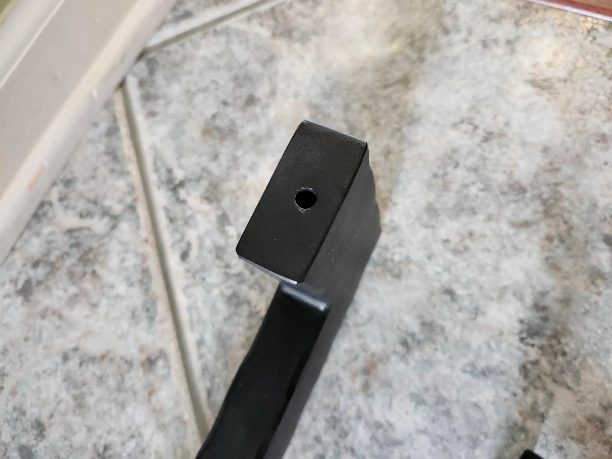 A black rectangular object with a small circular hole, positioned on a speckled granite or marble surface