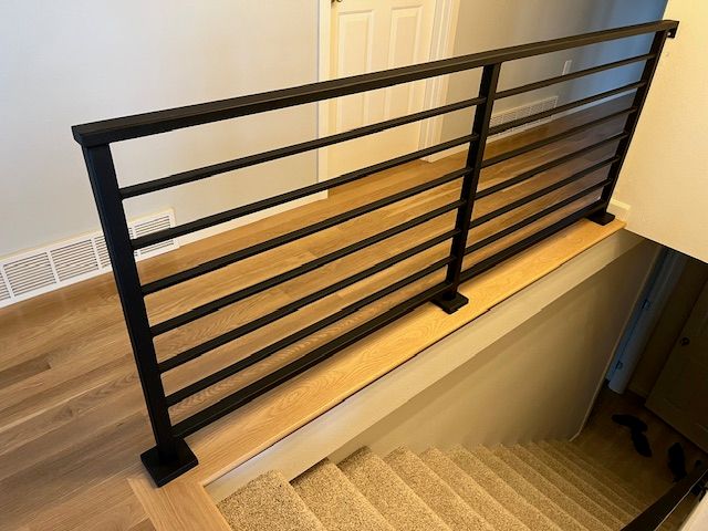 Modern black metal stair railing with horizontal bars installed on wooden stairs in a home interior