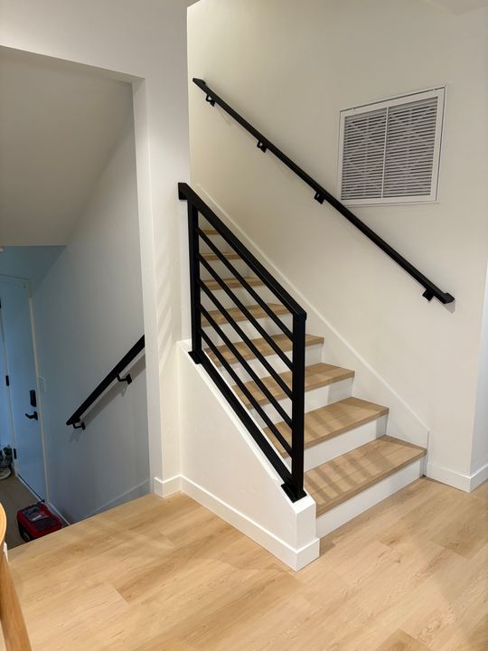 Modern staircase with black metal railings, wooden steps, and white walls in a contemporary home interior
