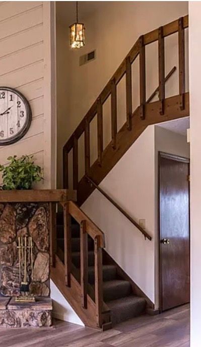 Interior staircase with wooden railings and stone fireplace in rustic home setting
