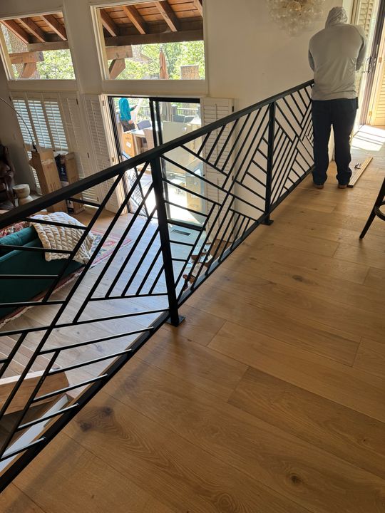 Modern staircase with black geometric metal railing and wooden steps in a contemporary home interior