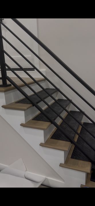 Modern staircase with wooden treads and black metal horizontal railings in a white interior space
