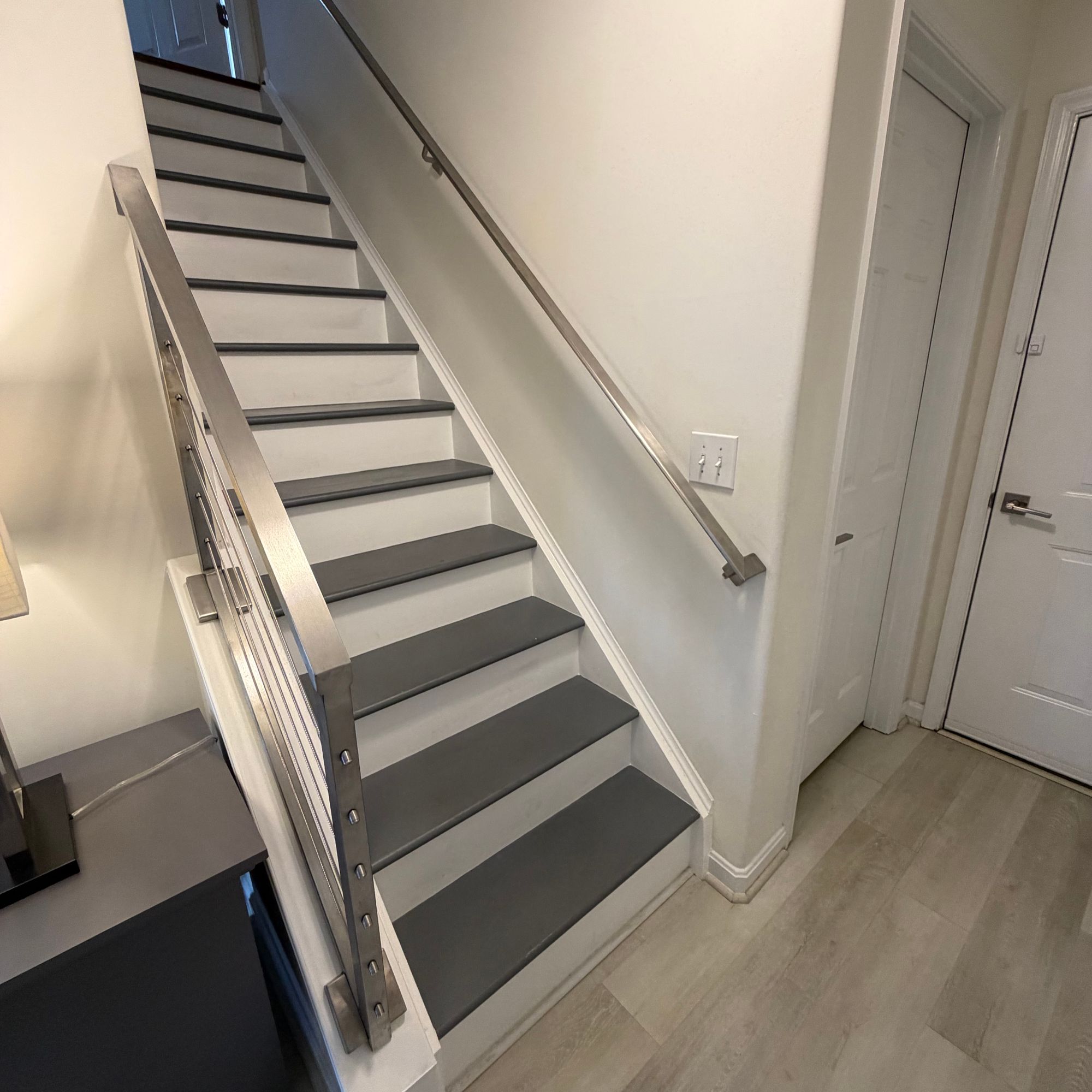 Modern staircase with white railings, gray treads, and cable railing system in a contemporary home interior