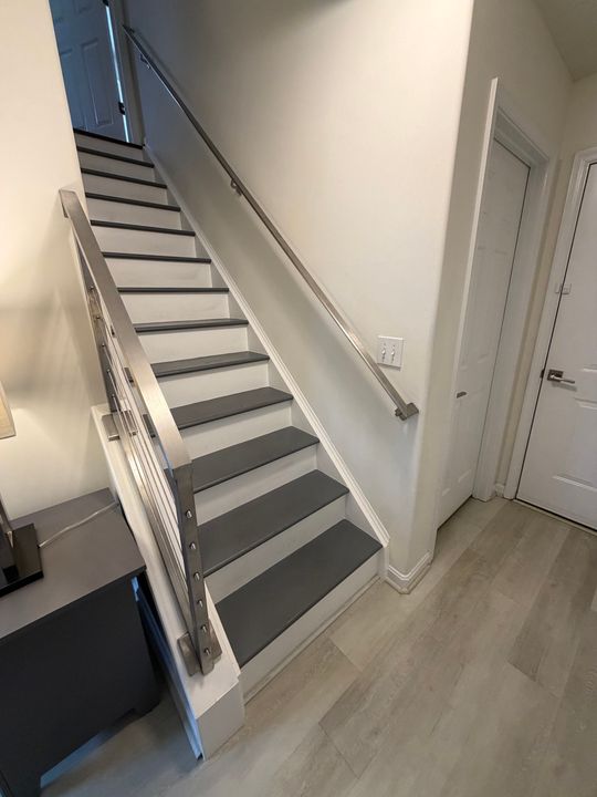 Modern staircase with white railings, gray treads, and cable railing system in a contemporary home interior