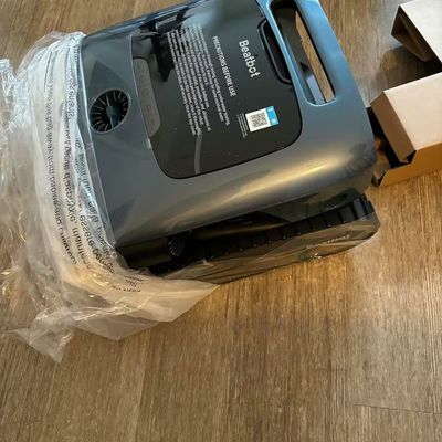 A Beatbot robotic cleaner in its original packaging on a wooden floor