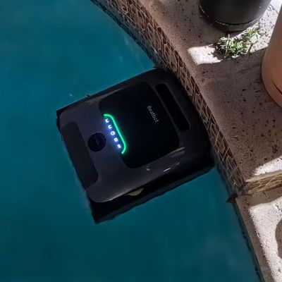 A robotic pool cleaner with LED lights floating in a swimming pool