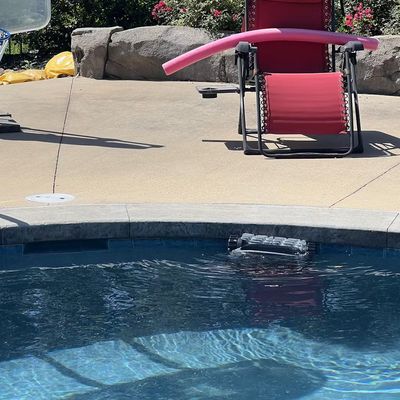 A red lounge chair beside a swimming pool with clear blue water