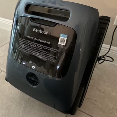 A Beatbot robotic pool cleaner sitting on tiled flooring