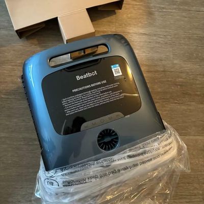 A blue Beatbot robotic pool cleaner in packaging on a wooden floor