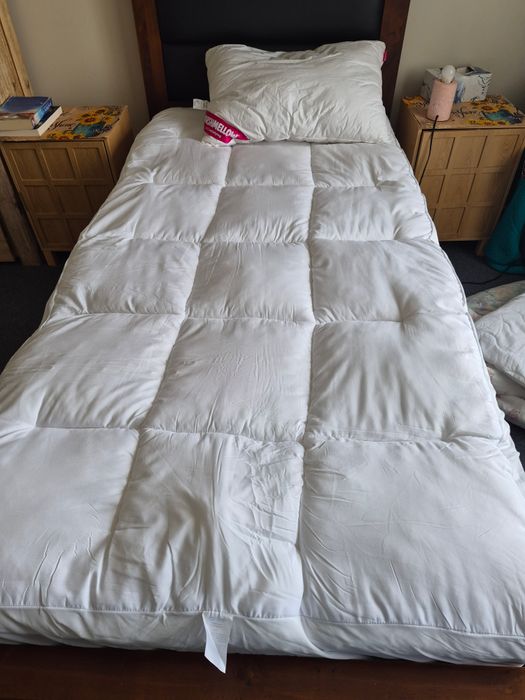 A customer's single bed seen from the foot, the topper filling the mattress edge to edge