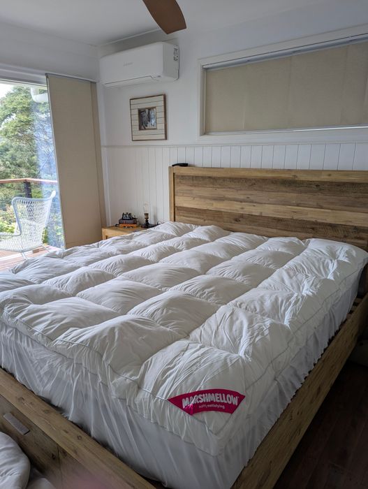 A customer's king bed with the Marshmellow topper on it, in a bright bedroom with a timber bedhead