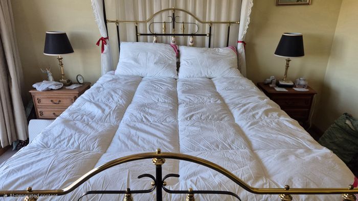 A customer's bed with a brass frame, the topper on the mattress and two pillows at the head