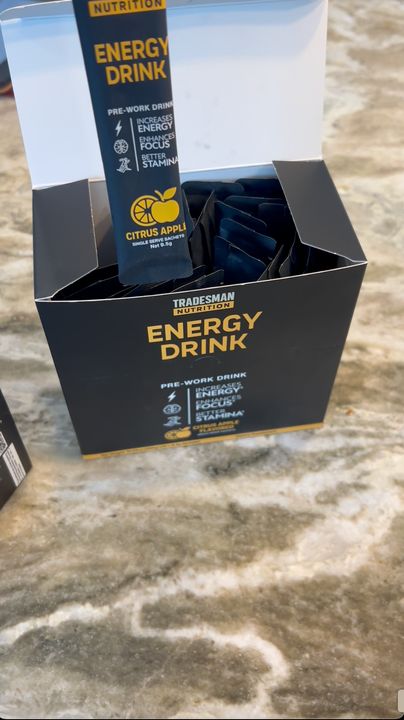 An open box of Tradesman Nutrition Energy Drink with a Citrus Apple stick held above it