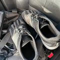 A pair of gray athletic running shoes sitting on a car seat next to a black backpack