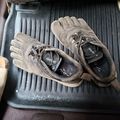 A pair of muddy athletic shoes sitting on a black rubber floor mat in what appears to be a vehicle