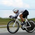 Cyclist in aerodynamic position riding a time trial bike on a road course