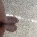 Bare feet of a young child on white sand beach with sunlight and shadows visible.