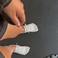 Person wearing white lace-up shoes with toe separators, viewed from above on a dark surface.