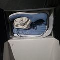 Blue athletic sneakers in an open shoe box with tissue paper
