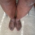 Overhead view of a person's legs and feet standing on a carpeted floor wearing silver heeled shoes.