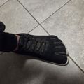 Person wearing black toe shoes with individual toe compartments, standing on tiled floor
