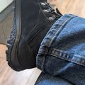 Person wearing black hiking boots and blue jeans sitting indoors