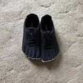 Black toe shoes with individual toe compartments and laces placed on textured concrete surface