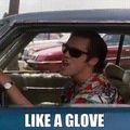 A person wearing sunglasses driving a car with text overlay reading "LIKE A GLOVE"