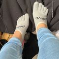 Person wearing light gray knit gloves with text on them, blue jeans, sitting with a dark colored bag or jacket nearby