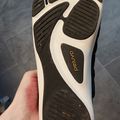 A hand holding a minimalist toe shoe or barefoot running shoe sole with individual toe compartments, featuring black and white design with "Pedal" branding