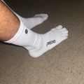 Person wearing white socks with "periva" branding, standing on a gray carpet floor.