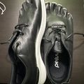 A pair of black leather casual shoes with white soles and black laces, displayed on a dark surface. The shoes have a textured leather upper and appear to be a slip-on or loafer style with lacing details. The brand name "peum" is visible on the insole.