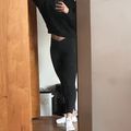 Person taking a mirror selfie wearing all black athletic wear and white sneakers in a home setting