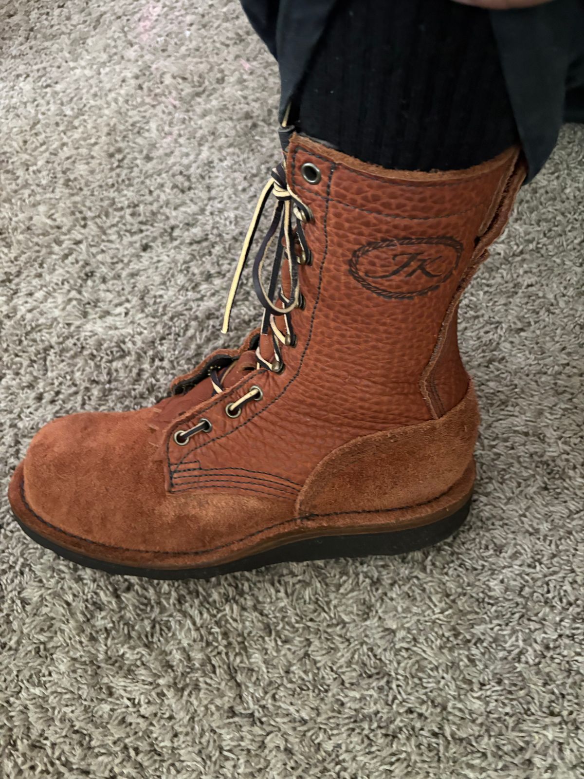 Brown leather lace-up boot worn on carpet