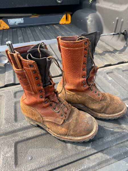 A pair of worn brown leather work boots sitting in the bed of a pickup truck