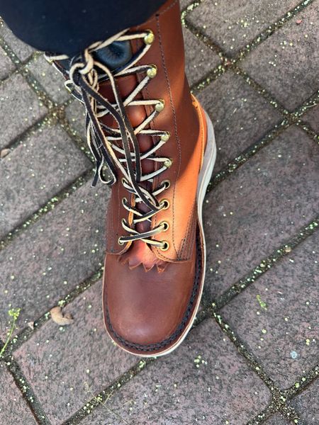 Brown leather boot with laces on cobblestone pavement