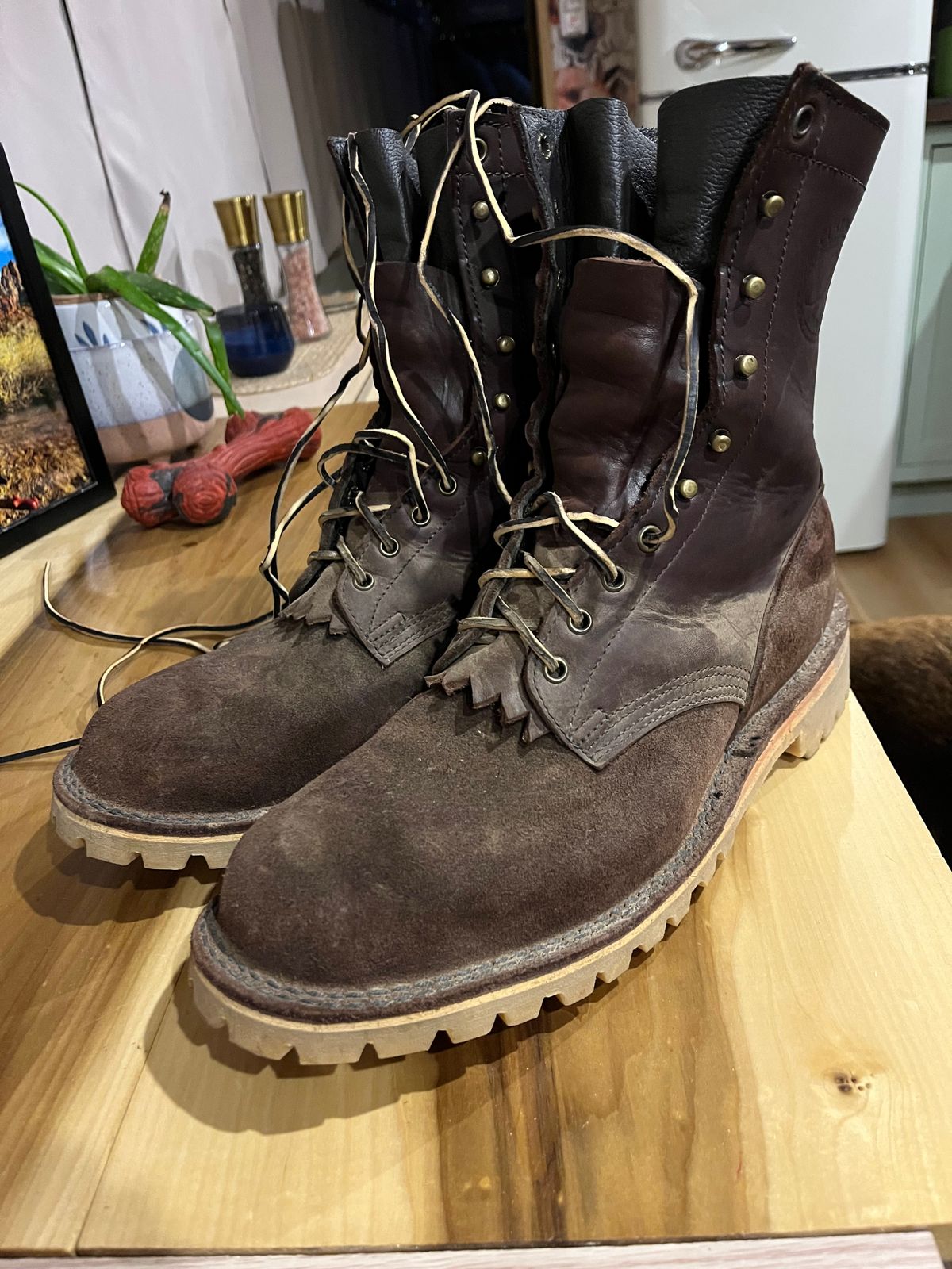 A pair of brown leather combat boots with laces sitting on a wooden surface