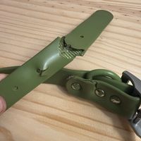 Green knife with sheath on wooden surface