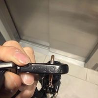 Image 10: Customer-uploaded image. Click to see more details. The image represents: A person's hand holding a black carabiner or clip with text engraved on it, photographed indoors near a white wall or cabinet.