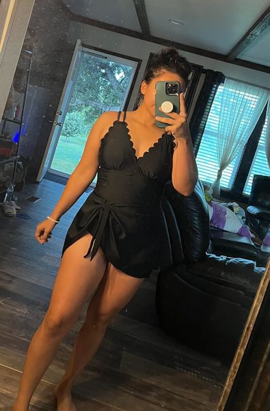 Person taking a mirror selfie in a bedroom with windows showing greenery outside