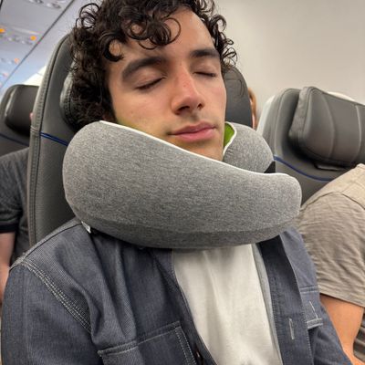 Customer wearing a gray travel pillow while sleeping on an airplane