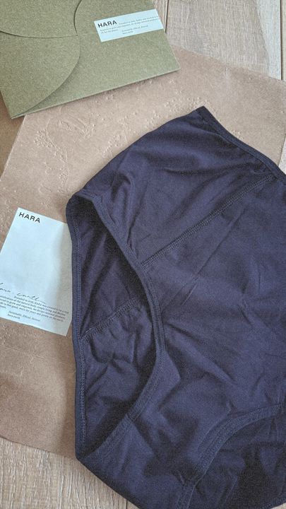 Navy period underwear with HARA tags on a textured surface