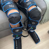 Customer-uploaded image. Click to see more details. The image represents: Person using compression therapy leg wraps with air chambers and control unit while sitting on a couch