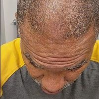 Customer-uploaded image. Click to see more details. The image represents: Person with short hair wearing a gray shirt looking downward