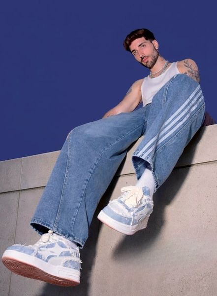 A person in casual clothing sitting on concrete steps against a blue background