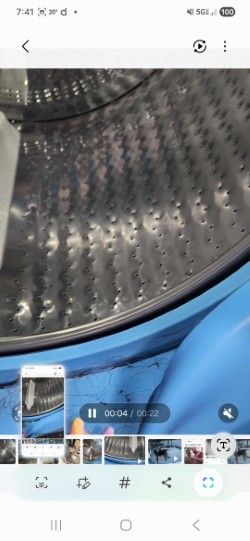 Interior view of a washing machine drum showing the perforated metal surface and blue exterior casing