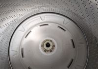 Customer-uploaded image. Click to see more details. The image represents: Interior view of a washing machine drum showing the perforated stainless steel walls and white plastic agitator at the bottom