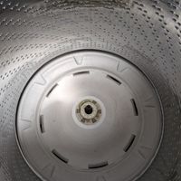 Customer-uploaded image. Click to see more details. The image represents: Interior view of a washing machine drum showing the perforated stainless steel walls and white plastic agitator at the bottom